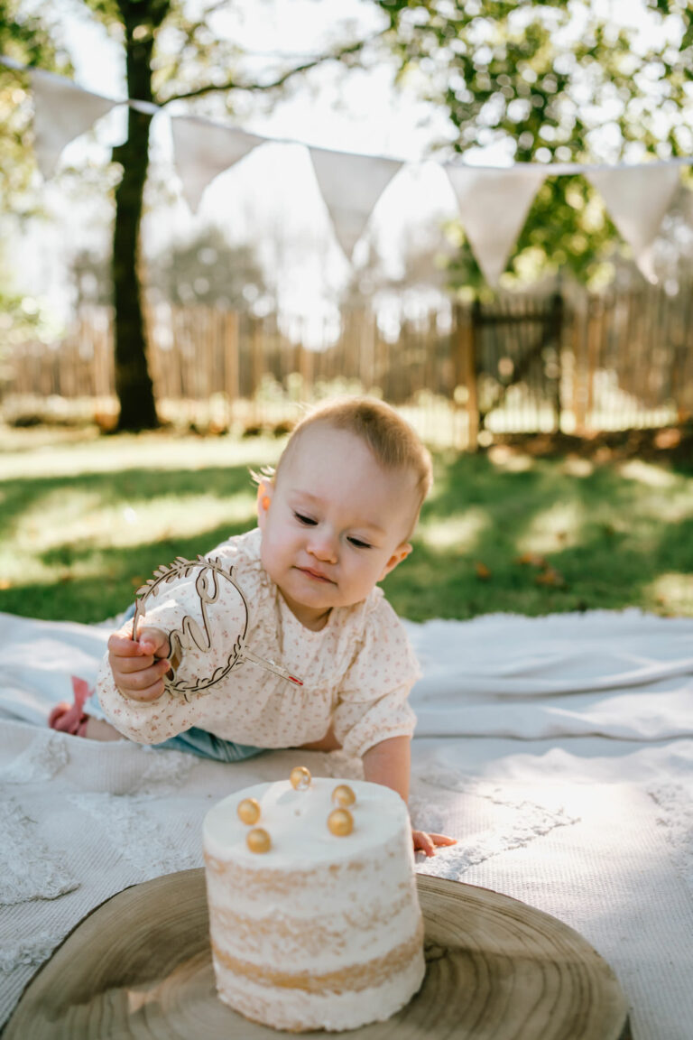 Cakesmash fotoshoot in de tuin met baby van 1 jaar verjaardag vieren met taart