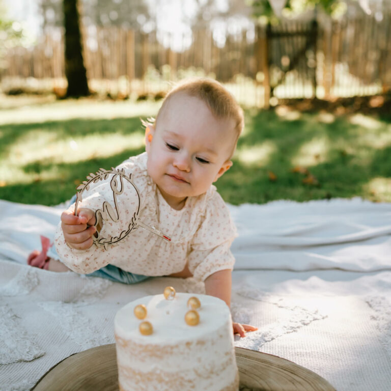 Cakesmash fotoshoot in de tuin met baby van 1 jaar verjaardag vieren met taart