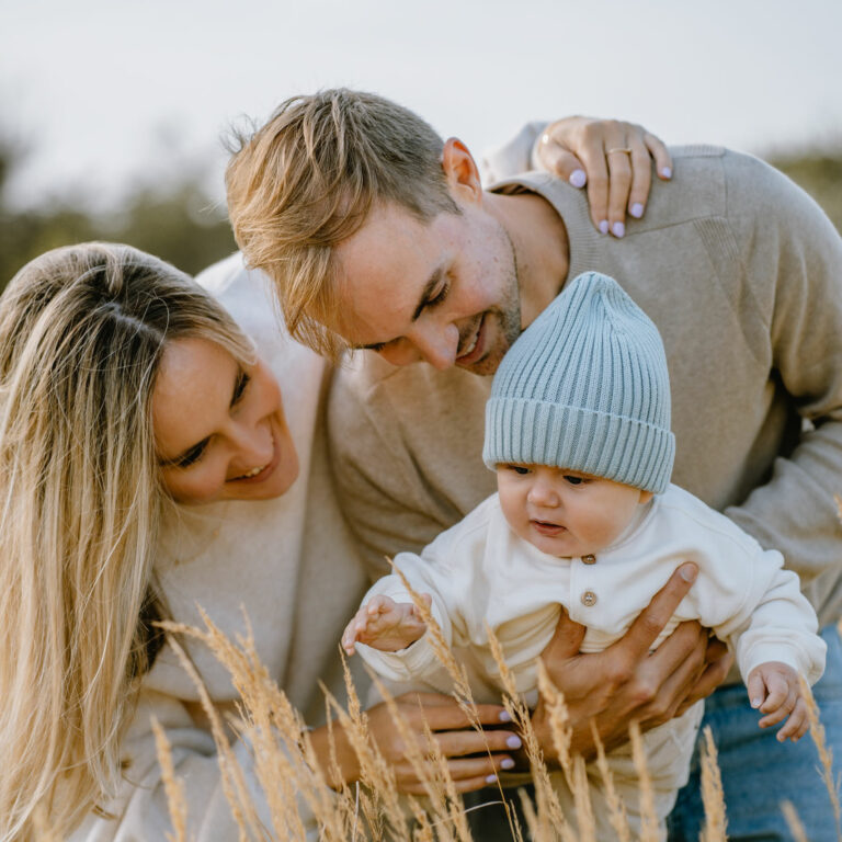 Ouders spelen samen met hun kindje in een natuurdomein tijdens gezinsshoot