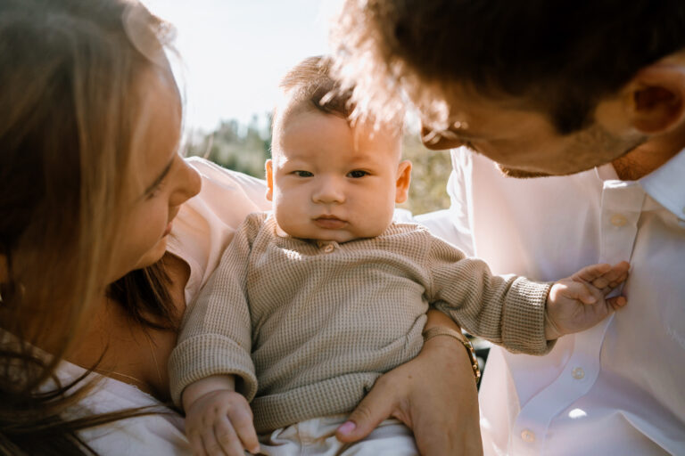 Gezinsfoto met baby tussen mama en papa in het zonnetje